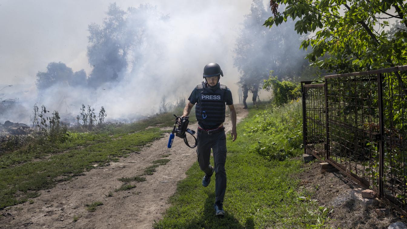 An AFP journalist runs as smoke rises behind after a bombardment in Bakhmut, Eastern Ukraine, on July 31, 2022.