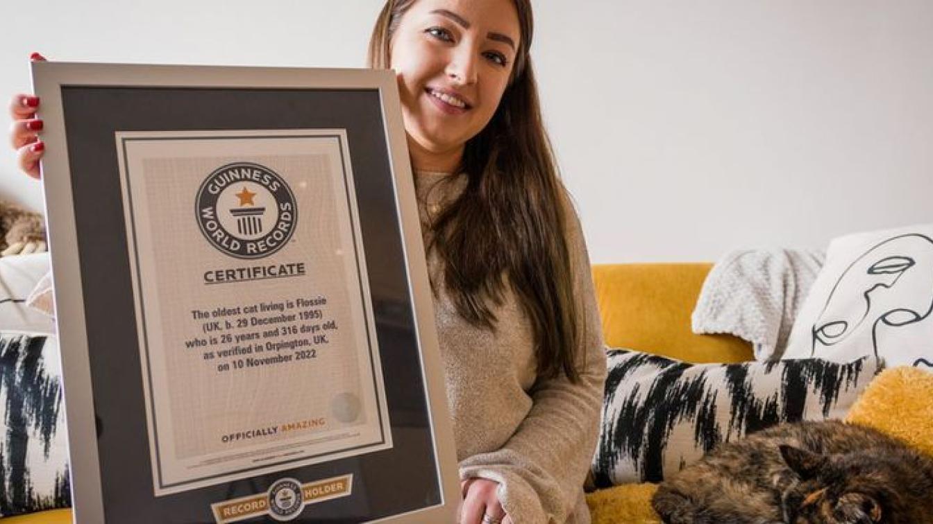 Besitzerin hält Guiness World Record Urkunde neben ältester Katze der Welt