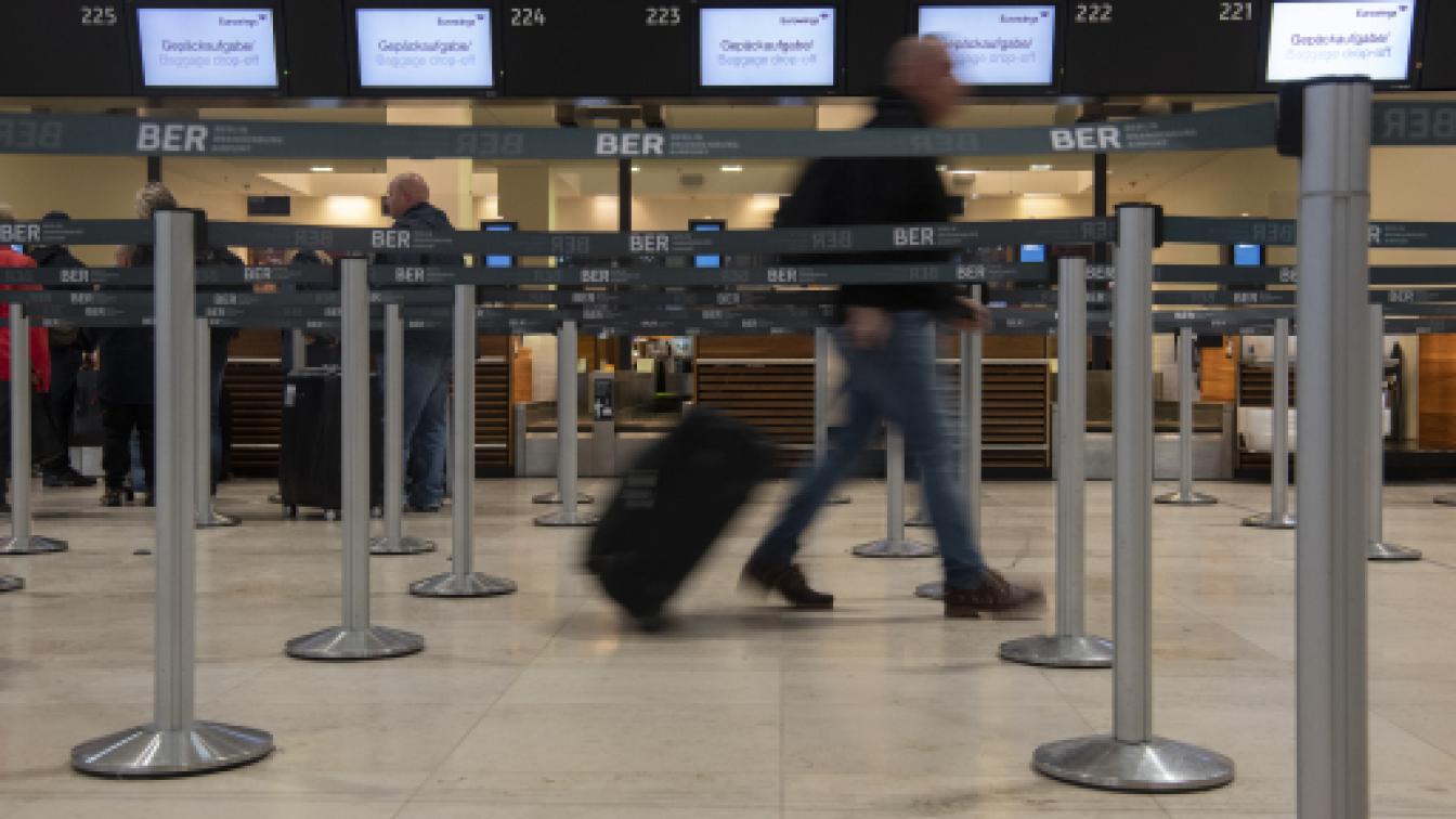 n Reisender geht mit einem Koffer zu einem Check-in-Schalter von Eurowings am Flughafen Berlin.