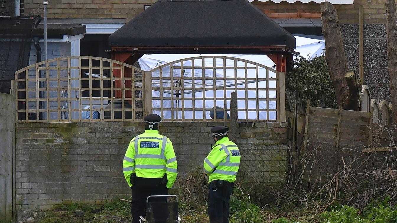 Zwei englische Polizeibeamte stehen vor einem Haus.