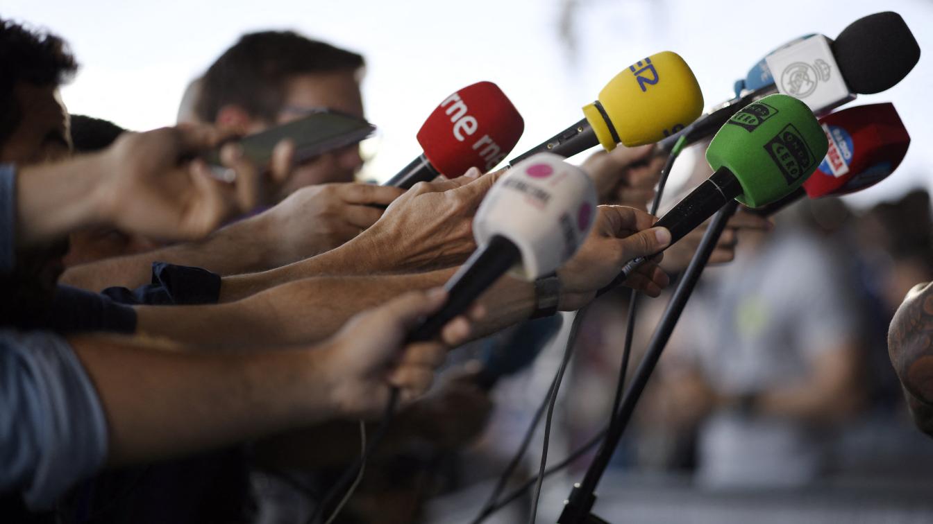 Mehrer Journalisten halten ein Mikrofon hoch